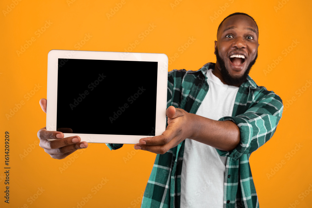 Poster great application. excited black guy showing tablet computer with empty screen to camera recommendin