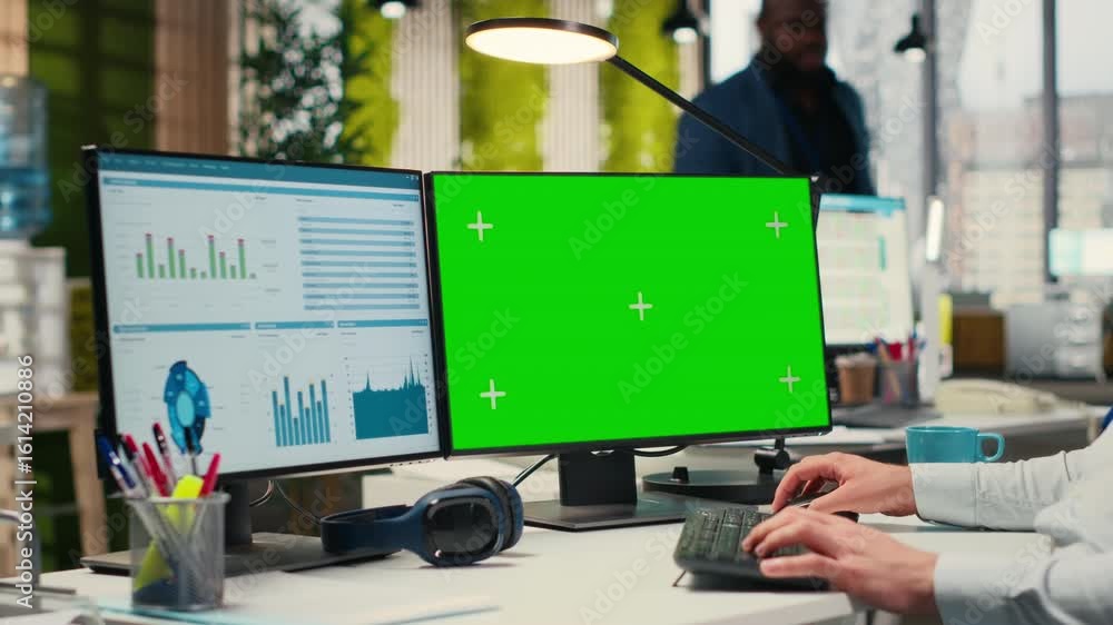 Poster employee engaged in business planning with a green screen in the office, does report writing to ensu