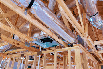 Construction workers install ductwork framing for residential ceiling in newly built home during...