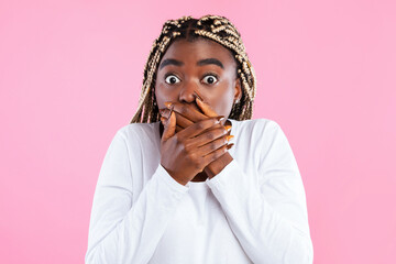 Oops. Portrait of surprised young african american woman covering her mouth with both hands and...