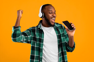 Mobile Karaoke App. Black Man Wearing Headphones Singing Holding Smartphone Like Microphone...