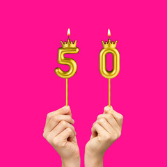 Birthday on a fuchsia background with the number 50 - Hands holding number-shaped candles
