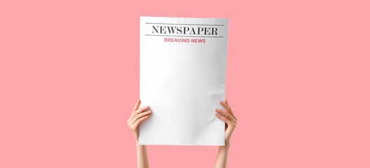 Hands holding newspaper on pink background