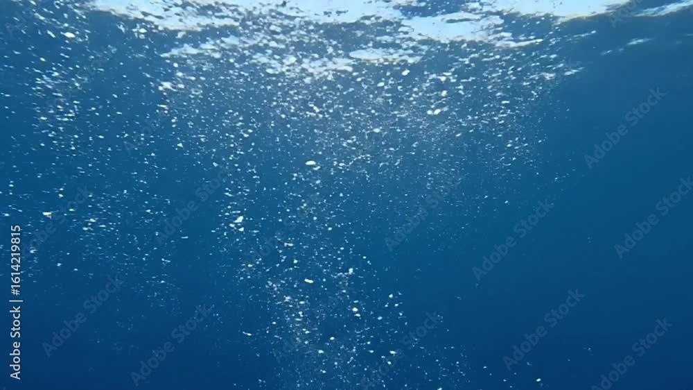 Poster underwater view with many small bubbles rising and sunlight filtering from above