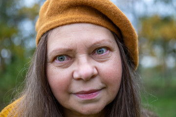 Happy senior woman enjoying fall season in warm beret, in autumn wearing cozy clothes in golden...