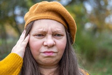 Autumn's beauty contrasts with woman's struggle, throbbing discomfort headache or migraine,...