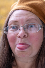 Closeup portrait senior woman making silly face sticking out tongue funny expression wrinkles aging humor outdoor autumn mood, Natural closeup elderly woman with humorous expression and joyful spirit