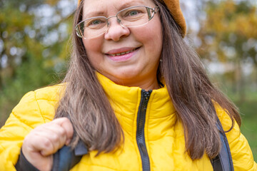 Happy middle-aged woman, Active mature tourist with backpack hiking in colorful autumn forest, nature lover, healthy lifestyle, Eco-friendly outdoor activity for older woman