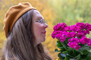closeup female face, mature woman smiling outdoors in autumn wearing cozy clothes, flower aster season, serene moment with aster blooms, essence fall, possibly causing allergy