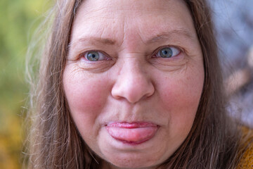 Closeup portrait senior woman making silly face sticking out tongue funny expression wrinkles aging humor outdoor autumn mood, Natural closeup elderly woman with humorous expression and joyful spirit