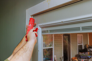 Carpenter is using caulk gun to seal gaps around door frame in home improvement effort.