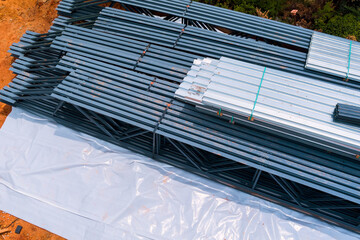 Steel beams are neatly arranged on construction site, with tarpaulins below for building...