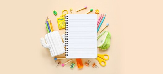 Notebook with different stationery on beige background