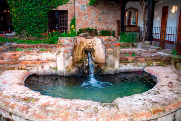 Rustic stone fountain with flowing water nestled in a lush colonial courtyard in La Antigua...