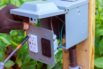 Technician connects wiring to an outdoor electrical outlet USB ports mounted on wooden post