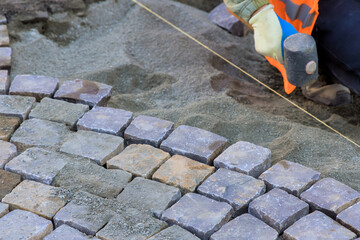 Worker skillfully positions cobblestones while ensuring alignment for new pathway construction