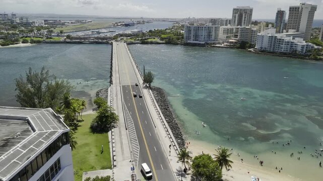 Drone flies west over causeway crossing the Laguna del Condado on sunny morning in San Juan, Puerto Rico