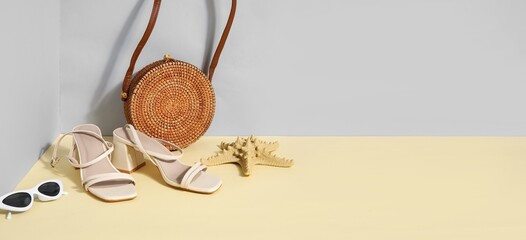 Female high heeled sandals with sunglasses and wicker bag on color background with space for text