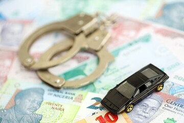 Nigerian naira currency money bills and toy car with handcuffs. The concept of car accident