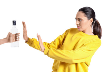 Young woman rejecting bottle of vodka on white background