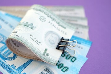 United Arab Emirates dirham money bills in big amount on purple. Finance and banking concept