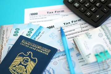 United Arab Emirates dirham money bills and calculator with tax form on blue. Taxation and...