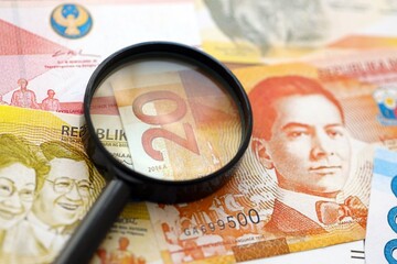 Philippines peso currency money bills and magnifying glass. The concept of financial monitoring and...