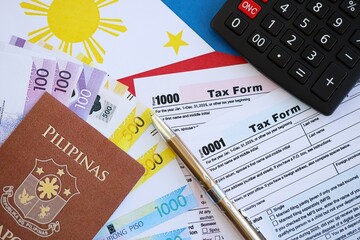Philippines peso money bills and calculator with tax form on flag. Taxation and accounting concept