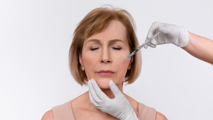 Aesthetic cosmetology concept. Senior woman getting hyaluronic acid or collagen injection on white...
