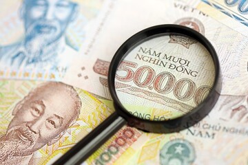 Vietnamese dong currency money bills and magnifying glass. The concept of financial monitoring and...