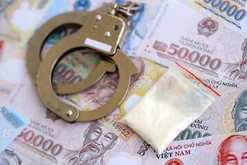 Vietnamese dong currency money bills and cocaine pack with handcuffs. The concept of drug crimes