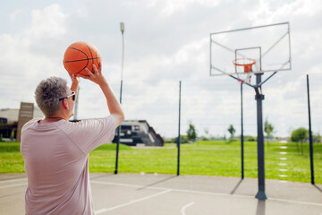 Man shooting basketball at a sunny outdoor court during leisurely afternoon