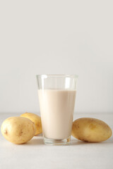 Glass of tasty potato milk on light background