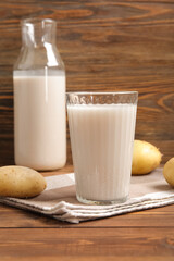 Glass of tasty potato milk on wooden background
