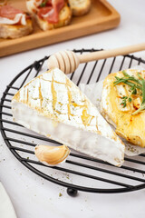 Grid with tasty baked Camembert cheese on grey background
