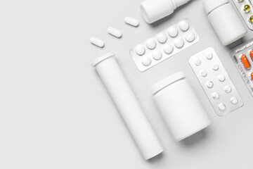 Different pills and bottles of medicines on grey background