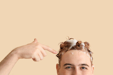 Young man with applied shampoo on his hair against beige background