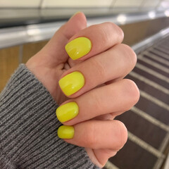 Beautiful bright manicure with light neon yellow colored nail polish close up