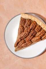 Plate with piece of tasty pecan pie on beige background
