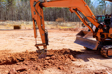 Excavator operates at construction site surrounded by construction site efficiently digs trench...