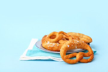Plate with tasty pretzels on blue background. Oktoberfest celebration