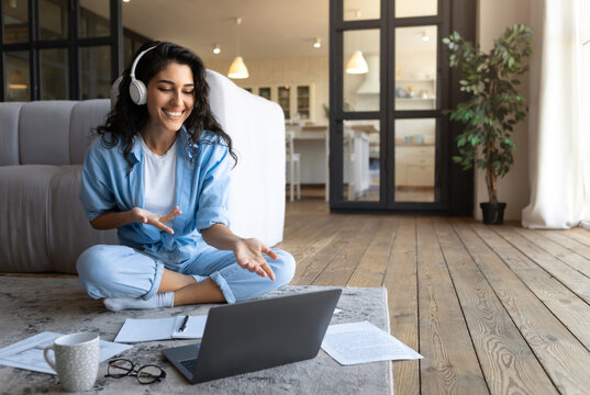 Portrait of cheerful Caucasian woman in headphones making video call, using laptop computer from home, free space. Happy millennial female having virtual online meeting or conference - Powered by Adobe