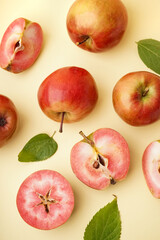 Sweet pink apples and leaves on yellow background