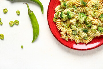 Plate of tasty pasta with broccoli and chili pepper on white background