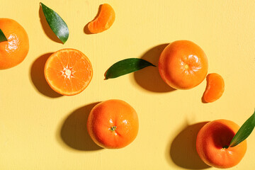 Sweet mandarins and leaves on yellow background