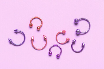 Colorful circular barbells for piercing on lilac background