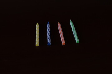 Varias velas de cumpleaños de diferentes colores colocadas en una mesa de madera de color marrón oscuro 
