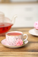 Cup of hibiscus tea with rose on table in kitchen