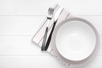 Table setting with plates and cutlery on white wooden background