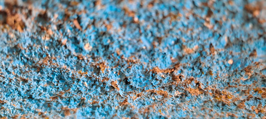 Close-up of an old painted blue concrete wall with rough texture, peeling paint, uneven and grungy...